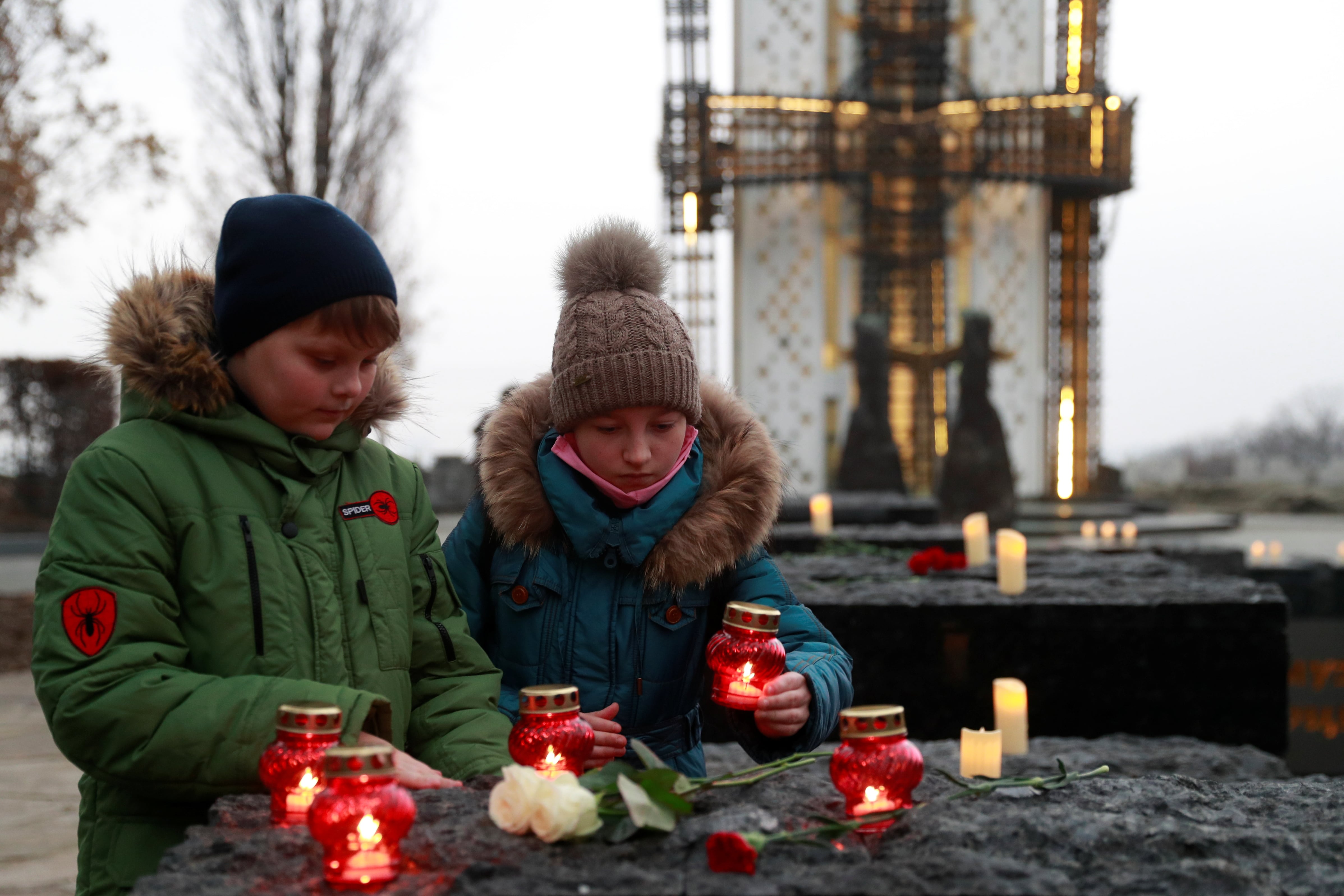 Unos niños colocan velas mientras visitan un monumento a las víctimas del Holodomor durante una ceremonia conmemorativa con motivo del 87.º aniversario de la hambruna de 1932-1933, en la que murieron de hambre millones de personas, en Kiev (Ucrania), el 28 de noviembre de 2020. REUTERS/Valentyn Ogirenko (REUTERS/Valentyn Ogirenko/Archivo)