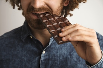 Un hombre comiendo una tableta de chocolate