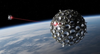 Un satélite LARES-2 esférico con múltiples retrorreflectores recibe un haz láser rojo. Al fondo se observa la curvatura de la Tierra y el espacio.