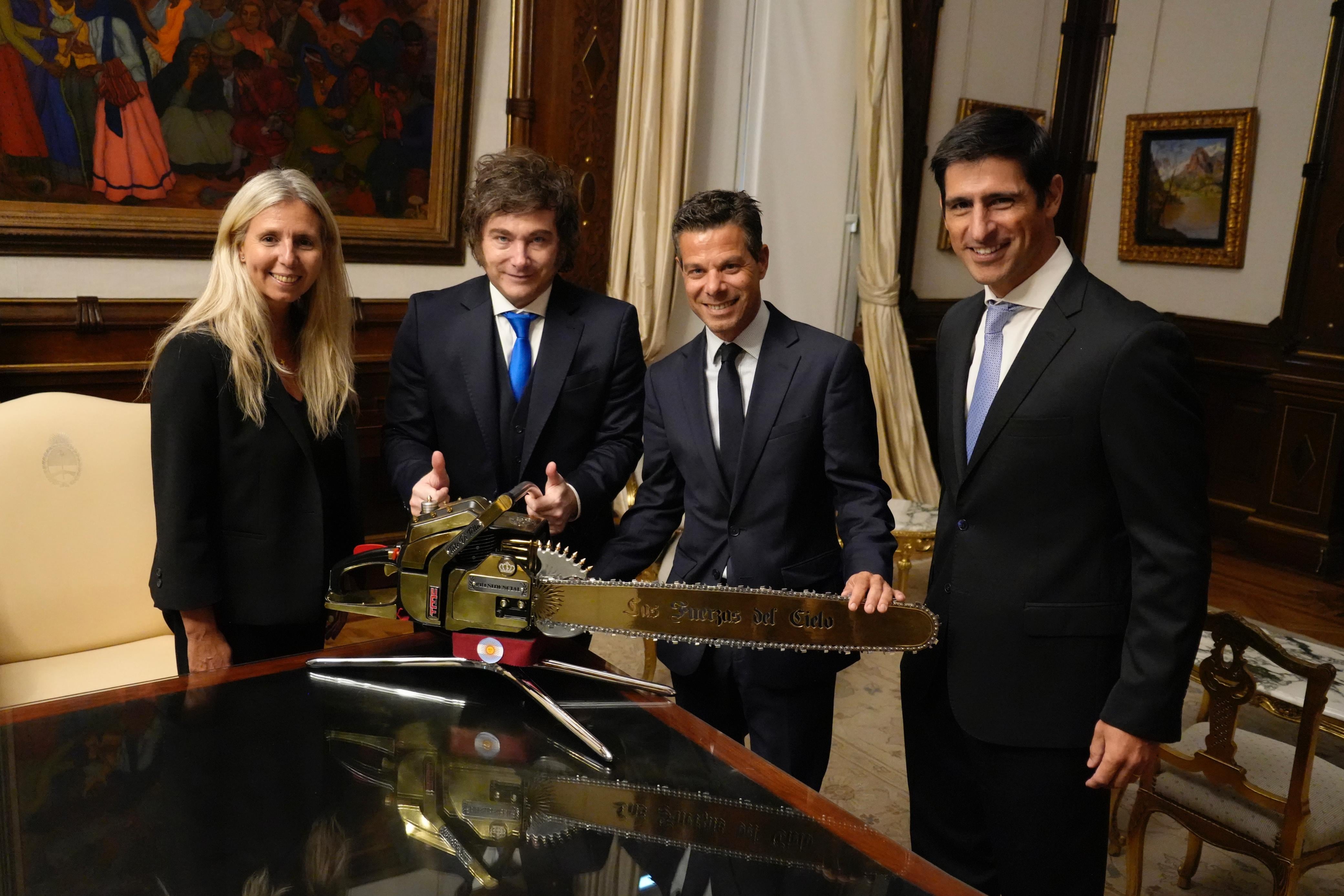 Javier Milei, presidente de Argentina, posa junto a directivos de Visa y la emblemática motosierra dorada con la inscripción 'Las Fuerzas del Cielo' durante un encuentro en un despacho oficial (Casa Rosada)