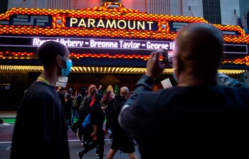 Fotografía tomada el pasado 31 de mayo en la que se captó a un ciudadano al registrar la fachada del teatro Paramount, en el que se iluminaron los nombres de Ahmaud Arbery, Breonna Taylor y George Floyd, durante una marcha contra la violencia racial, en Boston (Massachusetts, EE.UU.) EFE/CJ Gunther/Archivo