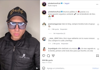 Primer plano de John Kelvin vistiendo una gorra negra con letras doradas, gafas de sol con lentes azules, y una chaqueta acolchada negra con el logo "JK John Kelvin"