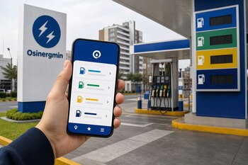 Una mano sostiene un teléfono inteligente con una aplicación de precios frente a un cartel de Osinergmin y surtidores de gasolina.