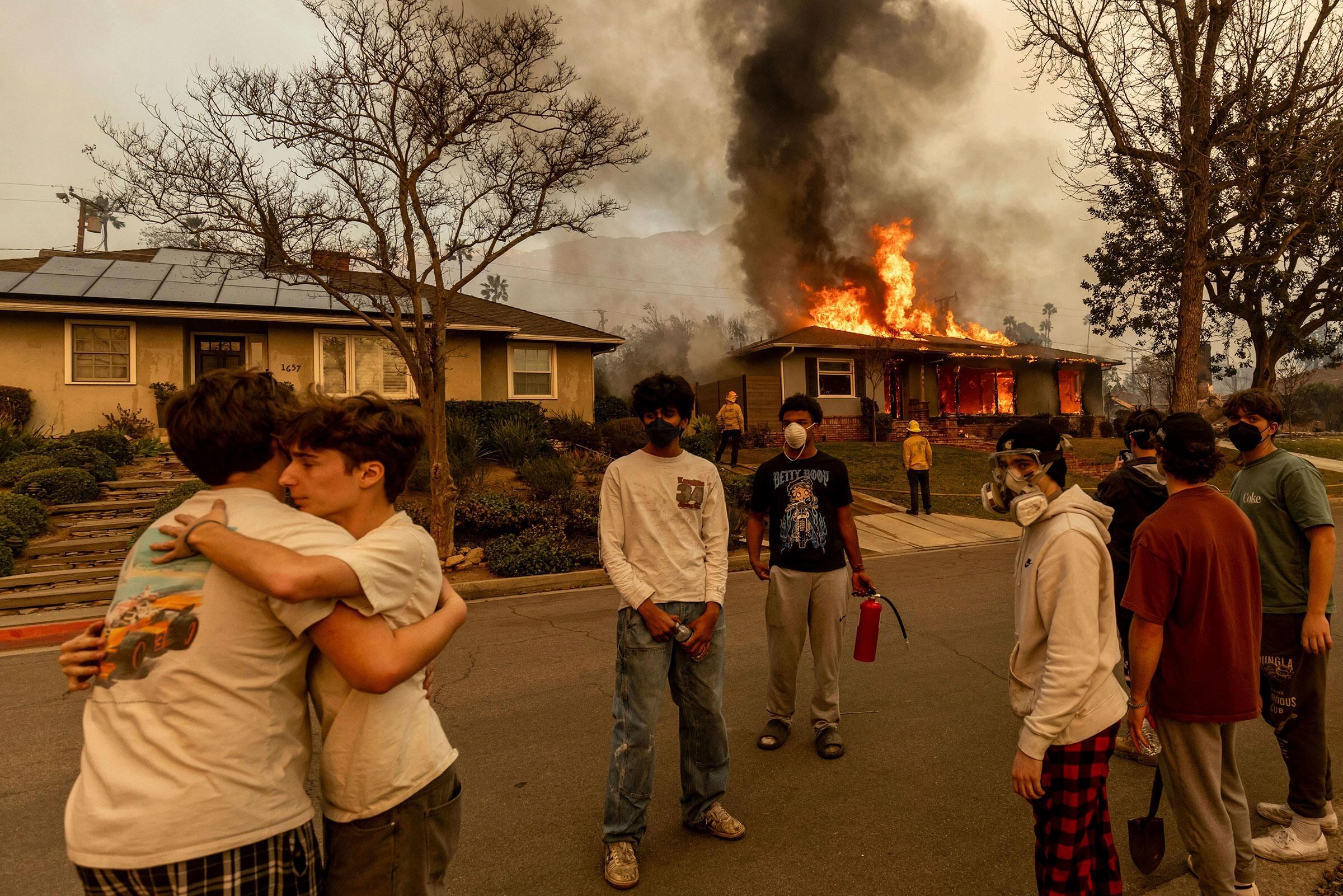 Los residentes se refugiaban fuera de una propiedad en llamas mientras el incendio Eaton arrasaba Altadena, California, el 8 de enero (Ethan Swope—AP)