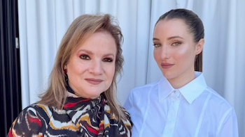 Lucía Galán, con blusa estampada multicolor, posa junto a su hija, de cabello recogido y camisa blanca, sobre un fondo blanco y negro