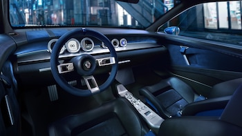 Interior de un automóvil con volante azul, logotipo de Renault, marcadores digitales redondos y asientos deportivos oscuros