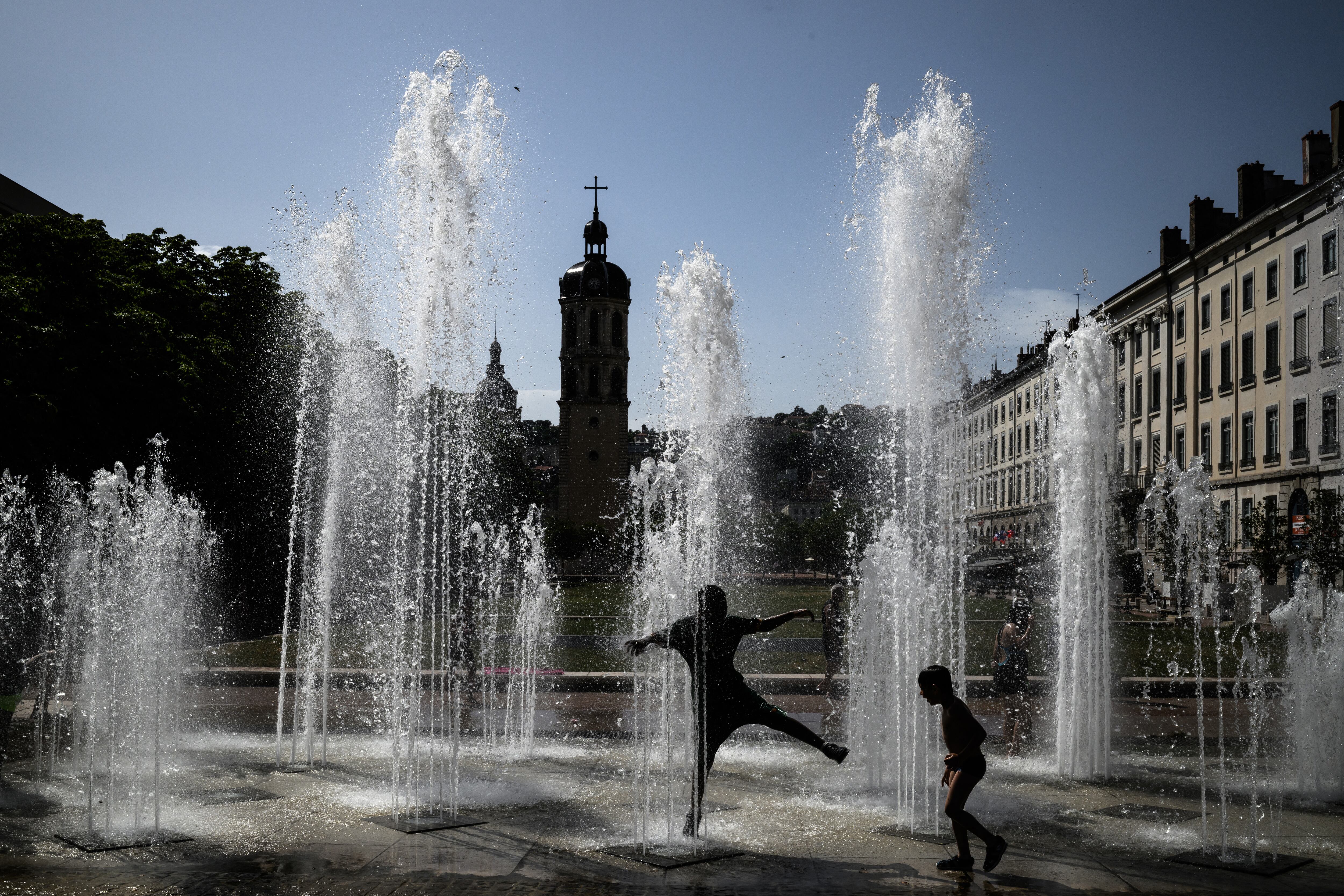 Chicos juegan con el agua y se refrescan en Lyon, Francia