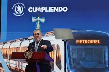 Bernardo Arévalo habla desde un podio frente a una pantalla que proyecta un tren con la palabra Metroriel, ante un público sentado