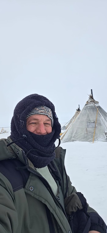 Grupo de personas, algunas vestidas con trajes tradicionales Nenet, posan sonrientes en la nieve frente a una tienda cónica, sosteniendo una camiseta de fútbol de Messi