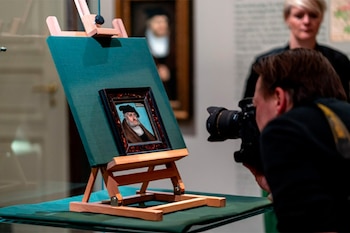 Primer plano de una pintura de Federico el Sabio sobre un caballete, siendo fotografiada por una persona, con otra persona de pie al fondo