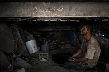 Un voluntario que busca cadáveres descansa bajo una viga de un edificio derrumbado en la que se lee «Dios es amor», en Caraballeda, estado de La Guaira, Venezuela, el 16 de julio de 2026 (Foto de Federico PARRA / AFP)