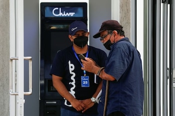 Un trabajador ayuda a un hombre con el uso de bitcoin frente a un cajero automático de "Chivo", la billetera digital respaldada por el gobierno salvadoreño, en San Salvador, El Salvador. 8 de septiembre de 2021. (REUTERS/Jose Cabezas)