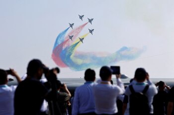 Un grupo de personas observa la actuación del equipo acrobático Bayi de la Fuerza Aérea del Ejército chino en Zhuhai el 12 de noviembre de 2024 (REUTERS/Tingshu Wang)