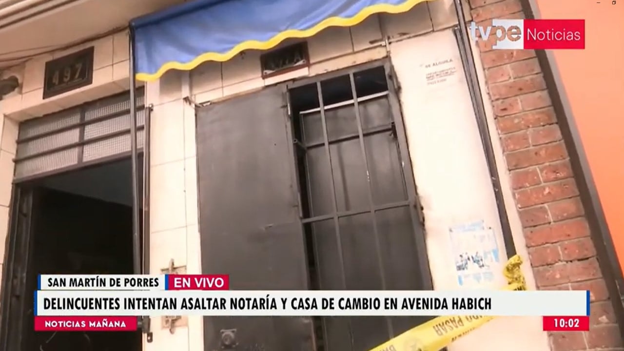 Una puerta metálica forzada y acordonada con cinta de seguridad permanece vigilada tras un asalto a una notaría y casa de cambio en la avenida Habich, en San Martín de Porres.