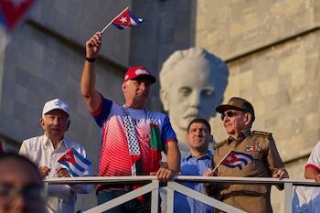 El dictador de Cuba Miguel Diaz-Canel ondea una bandera cubana mientras mira el desfile del Día del Trabajo junto a Raúl Castro, segundo de derecha a izquierda, y Raul Guillermo Rodríguez Castro, nieto de Raúl Castro, en la Plaza de la Revolución en La Habana, el 1 de mayo de 2025 (AP/Ramon Espinosa)