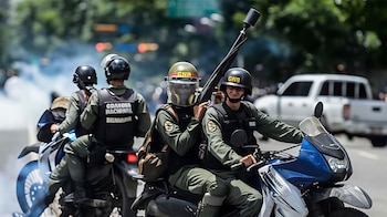 Cuatro funcionarios con casco y chaleco antibalas transitan en motocicletas; uno de ellos sostiene un lanzador de gas lacrimógeno