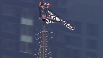 Dos personas suben a la cima del Empire State Building y despliegan una pancarta a favor de la paz