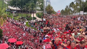 Una multitud de personas en un evento al aire libre, con muchas vestimentas rojas y azules, una bandera de Noruega, árboles y vehículos policiales