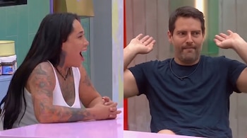 Karina Torres sentada frente a una mesa rosa gesticula a la izquierda mientras Memo Schutz levanta las manos a la derecha.