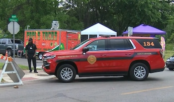 Un vehículo rojo de Toledo Fire Rescue, número 134, estacionado en una calle con un camión de comida 'Papi's Tacos' y tiendas de campaña al fondo