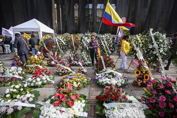 Demonstrators stand among flower wreaths
