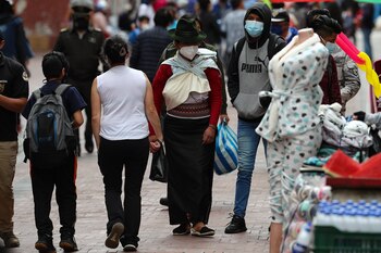 Varias personas caminan frente a comercios informales, en las calles de Quito (EFE/ José Jácome)