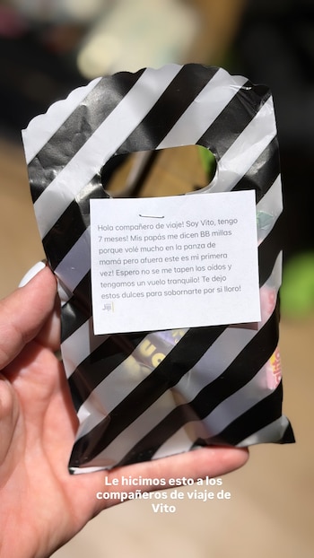 Una mano sostiene una pequeña bolsa a rayas negras y blancas con dulces y un mensaje impreso pegado en el frente