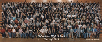 Gran grupo de cientos de estudiantes de la Clase de 1999 de Columbine High School, sentados en gradas de madera en un gimnasio, mirando al frente