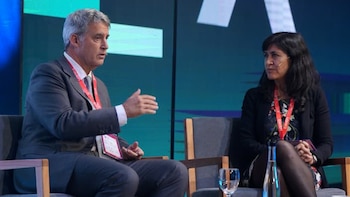 Alfonso Prat Gay, un hombre de pelo gris con traje, habla gesticulando en un panel, sentado junto a una mujer de cabello oscuro que lo observa