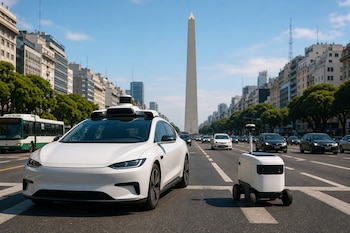 Un auto blanco con sensores en el techo y un pequeño robot de entregas avanzan por una avenida junto al Obelisco de Buenos Aires.