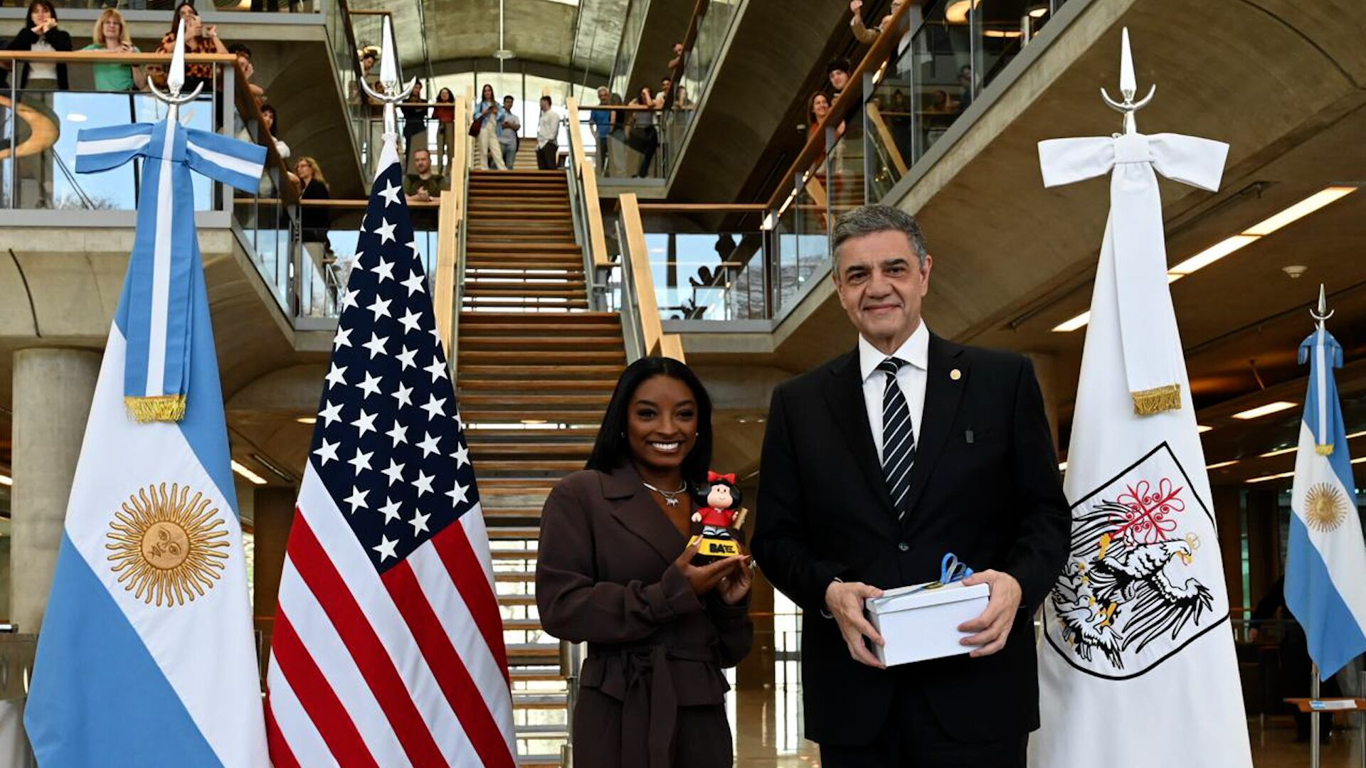 Simone Biles posa junto al jefe de Gobierno porteño, Jorge Macri, y la Mafalda en miniatura que le obsequiaron durante su visita a la Casa de Gobierno de CABA.