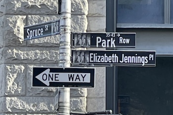Un poste con cuatro señales de calle: Spruce St, Park Row, Elizabeth Jennings Pl y un letrero de sentido único hacia la izquierda