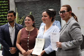 Cuatro personas, tres mujeres y un hombre, posan sonriendo. Dos mujeres sostienen documentos con el logo y el texto Congreso República