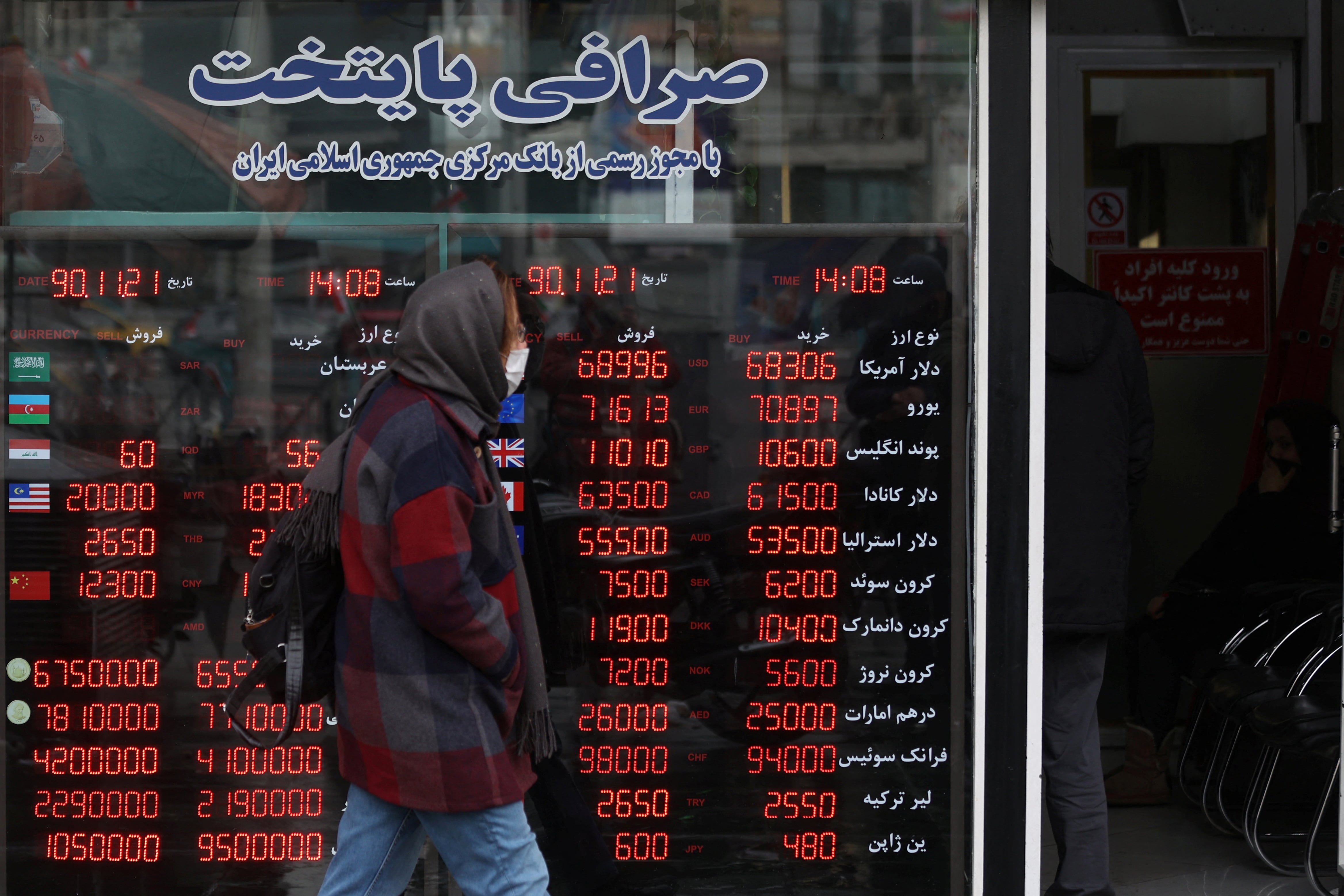 La gente pasa junto a un cartel en una casa de cambio mientras el rial iraní se deprecia, en Teherán, Irán. Majid Asgaripour/WANA vía REUTERS