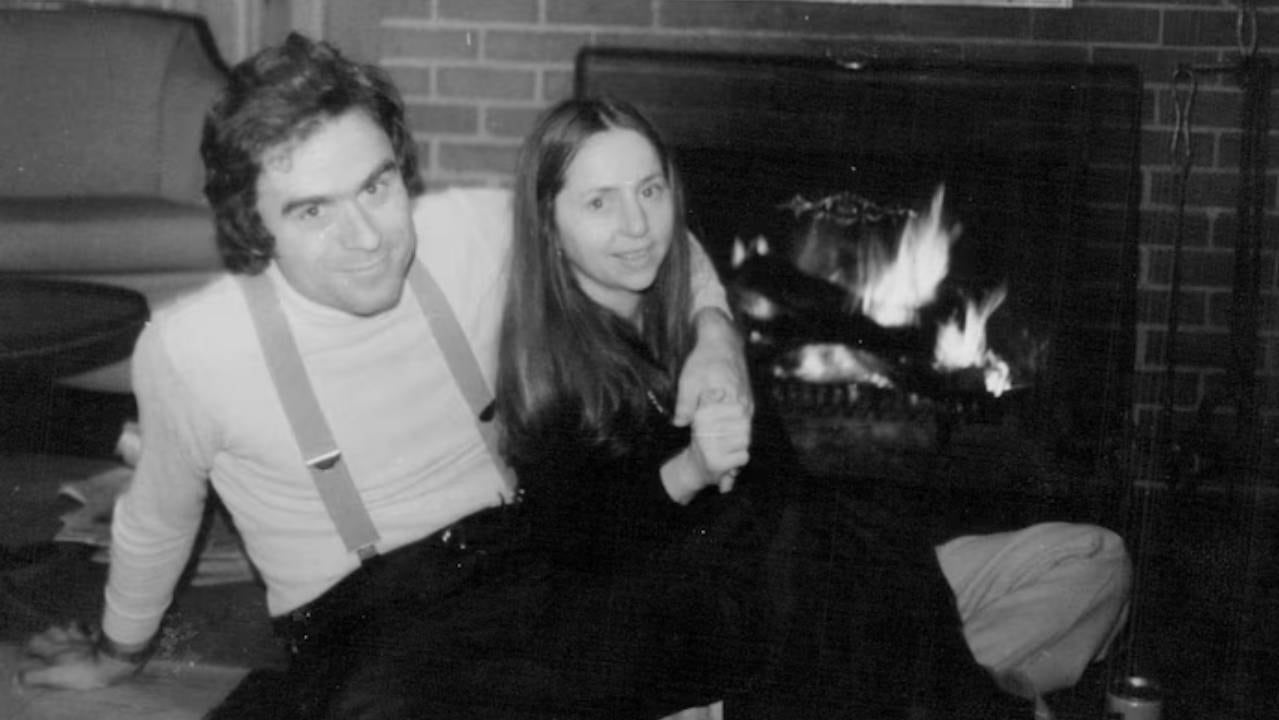 Ted Bundy y Elizabeth Kendall posan para una foto íntima en blanco y negro frente a una chimenea encendida, un momento previo al descubrimiento de la verdadera identidad del asesino serial.