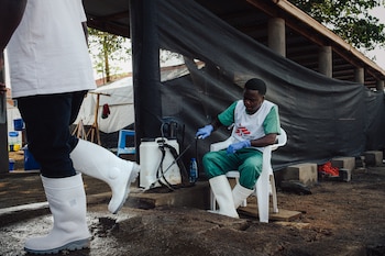 Serge, de 22 años, rocía el calzado de quienes entran en la zona de riesgo del centro Elykia, en Bunia. Es una de las medidas de bioseguridad con las que MSF intenta evitar contagios: la médica Carolina Nanclares dijo que su equipo sigue protocolos "muy estrictos" y que ninguno de sus integrantes se enfermó. (Foto: Julien Dewarichet/MSF, 23 de julio)
