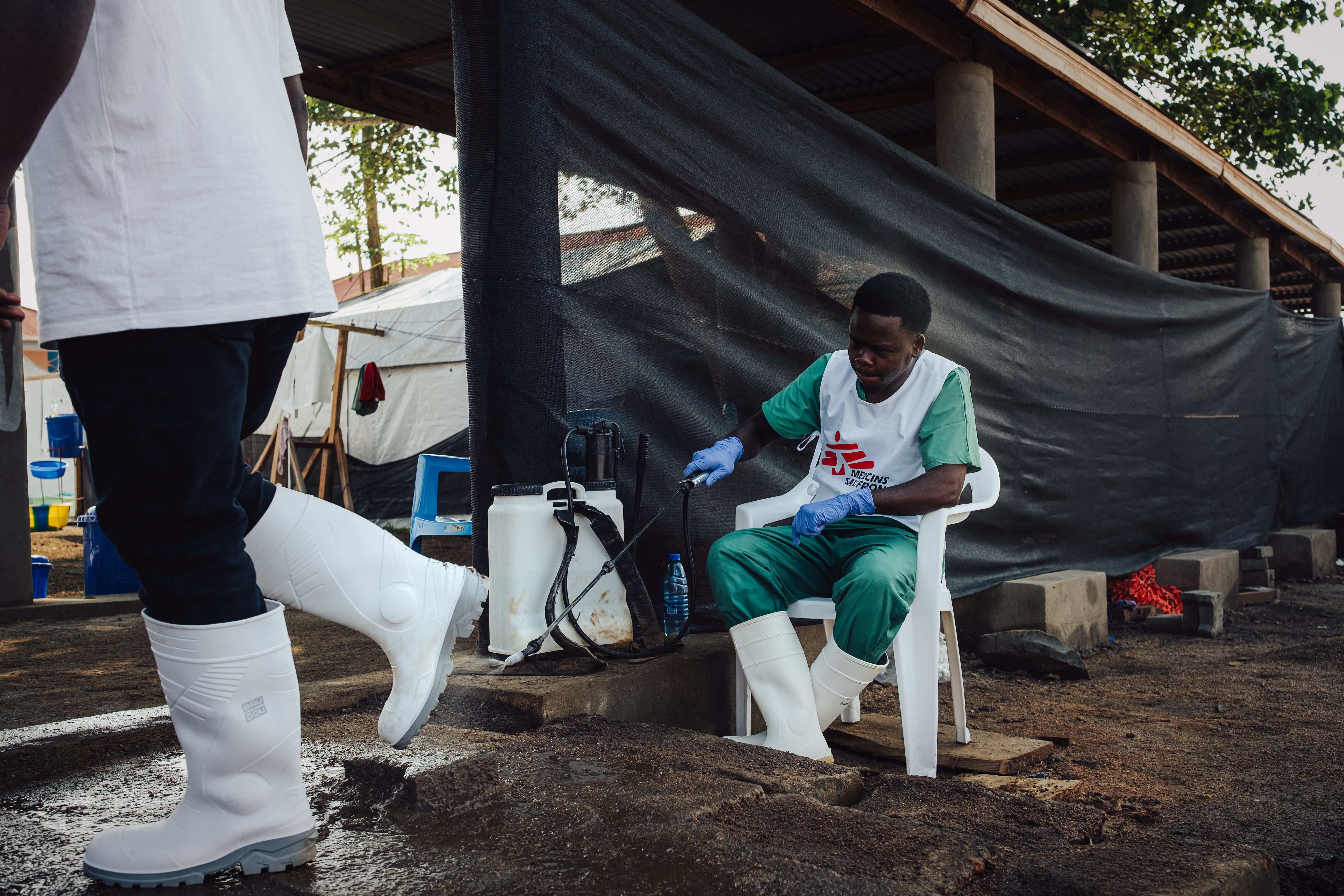 Serge, de 22 años, rocía el calzado de quienes entran en la zona de riesgo del centro Elykia, en Bunia. Es una de las medidas de bioseguridad con las que MSF intenta evitar contagios: la médica Carolina Nanclares dijo que su equipo sigue protocolos