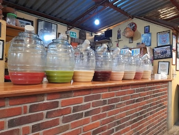 Ocho vitroleros de vidrio con líquidos de diferentes colores alineados sobre un mostrador de ladrillos dentro de un local