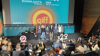 Diez personas de pie en un escenario. Una pantalla grande con logo GIFF y texto. Logotipos del GIFF y el número 29 en el escenario y pared. Audiencia abajo