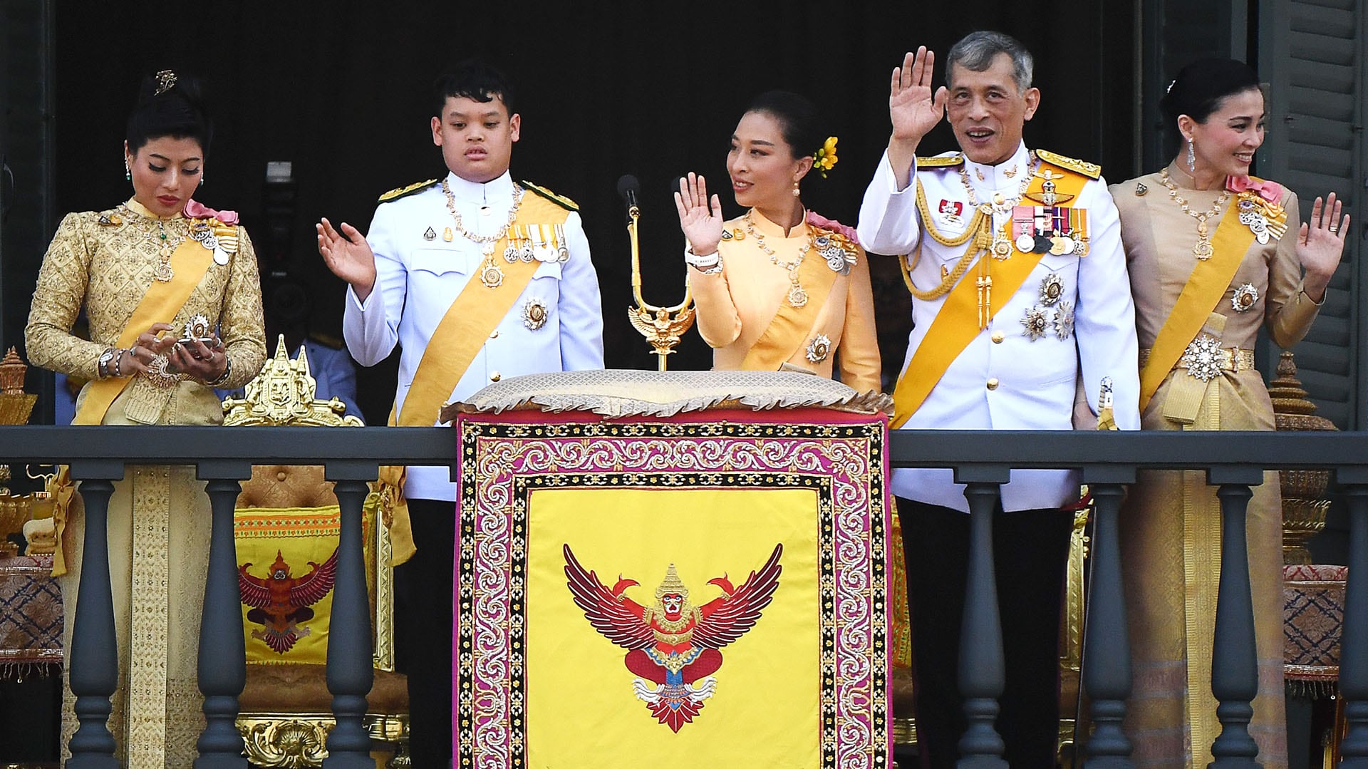 La princesa Sirivannavari Nariratana de Tailandia utiliza su teléfono móvil mientras su hermano, el príncipe Dipangkorn Rasmijoti, su hermana, la princesa Bajrakitiyabha Mahidol, su padre, el rey Maha Vajiralongkorn, y la reina Suthida saludan a los simpatizantes desde el balcón del Suddhaisavarya Prasad Hall del Gran Palacio, mientras conceden una audiencia pública el último día de su coronación real en Bangkok, el 6 de mayo de 2019 (Jewel Samad/AFP/Archivo)