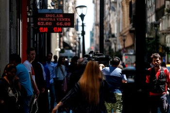 Transeúntes caminan bajo un tablero