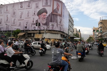 Motocicletas pasan ante un cartel que muestra una imagen del fallecido líder supremo de irán, el ayatolá Alí Jamenei, fallecido en ataques de Estados Unidos e Israel el 28 de febrero, con el puño enmarcado entre puños enmarcados de seguidores, en el centro de Teherán, Irán, el miércoles 6 de mayo de 2026. (AP Foto/Vahid Salemi)