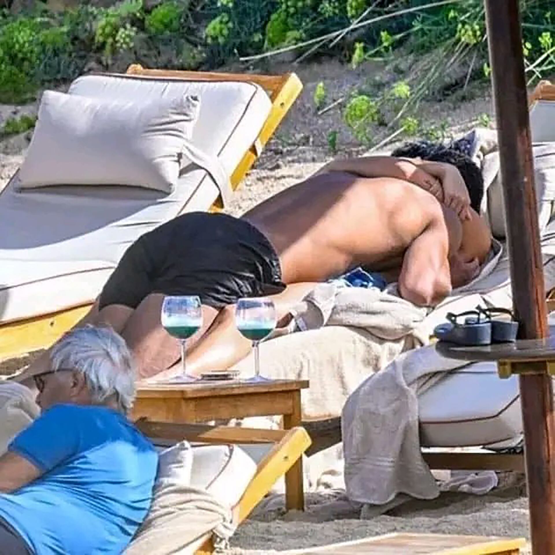 Besos en la reposera. Cerca, un turista los ignora