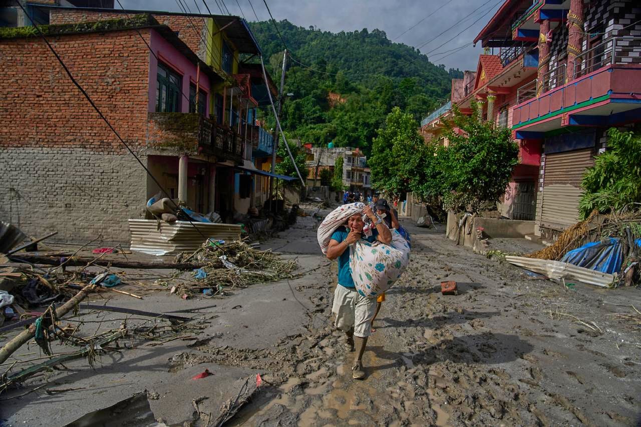Los residentes transportan sus pertenencias mientras caminan hacia zonas más seguras tras las inundaciones repentinas en Devighat, en el distrito de Nuwakot, Nepal, el jueves 27 de agosto de 2026 (AP/Niranjan Shrestha)