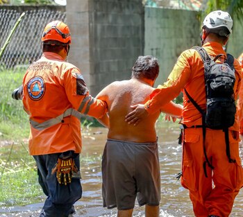 Elementos de Protección Civil asistieron a un habitante durante una evacuación en una zona afectada por inundaciones tras el paso de la tormenta Cristina en El Salvador (Cortesía Secretaría de Prensa).