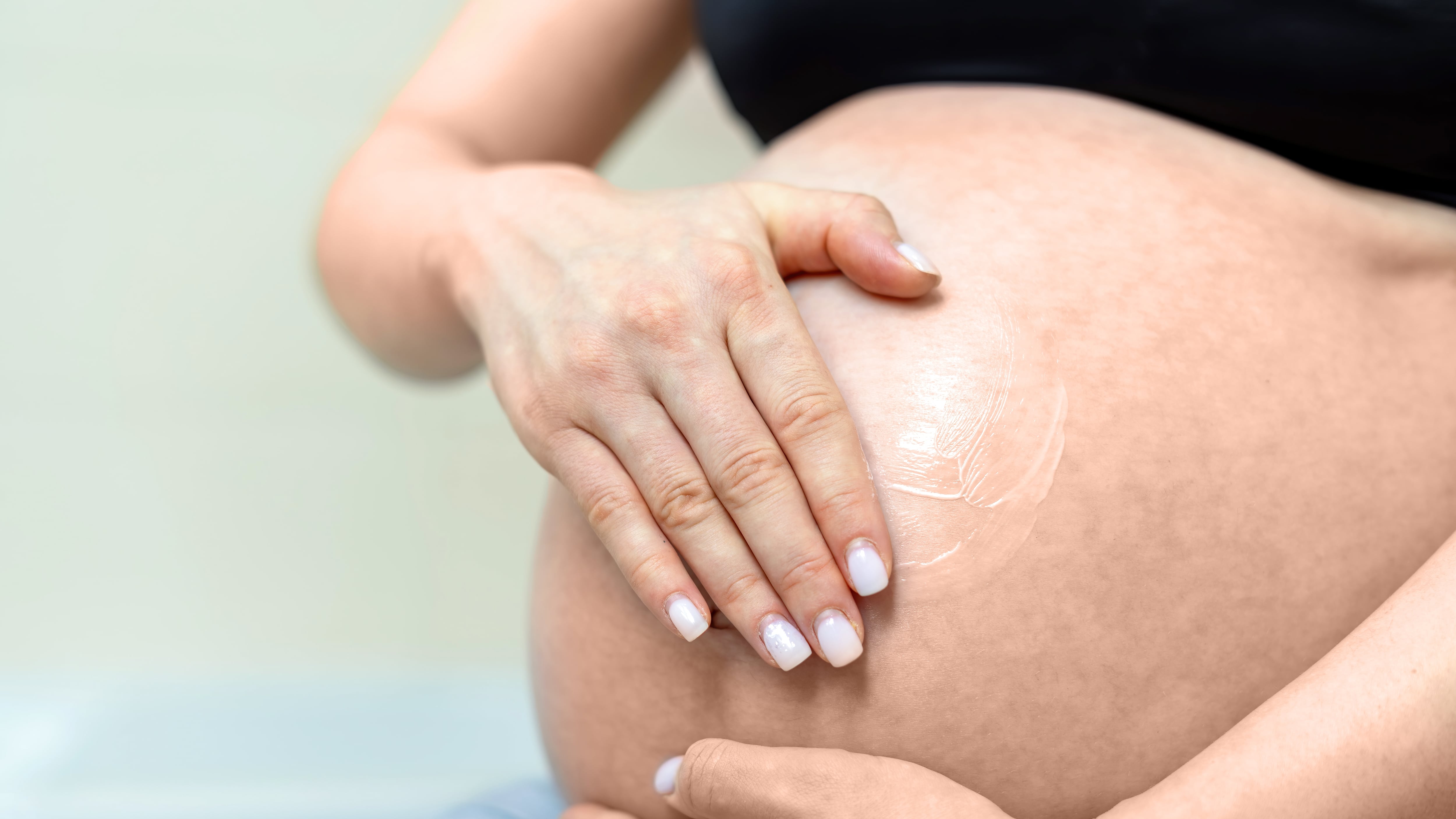 Mujer embarazada que se extiende crema en la barriga. (Freepik)
