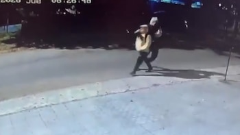 Imagen de videovigilancia de dos personas en una calle cubierta de nieve, una con chaqueta clara y la otra con ropa oscura, por la noche