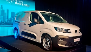 Una van Peugeot Partner blanca de perfil, iluminada con luces azules en su parte trasera, sobre una plataforma oscura con un fondo negro y pantalla