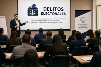 Un hombre expone ante asistentes sentados frente a una pantalla proyectada con el texto Delitos Electorales.