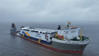 Un barco de carga de gran tamaño de la empresa Boskalis, con el nombre Black Marlin, lleva sobre su cubierta un ferry blanco de Buquebus